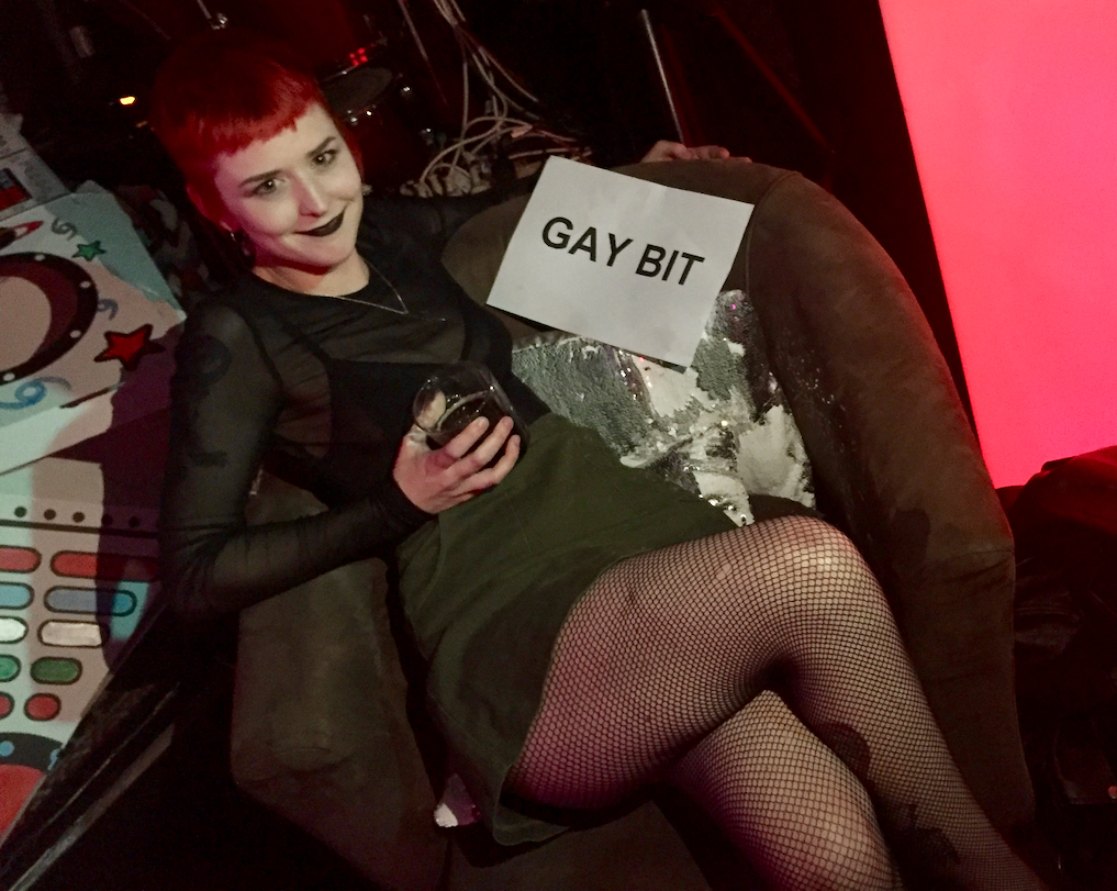 Zoe smiling holding sign that says Gay Bit